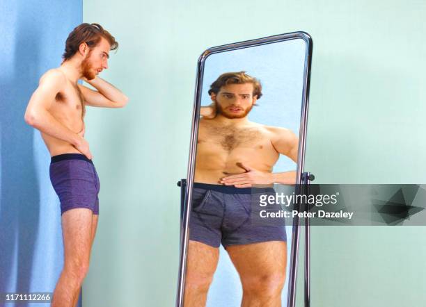 man seeing an illusion of a fatter self in mirror - negative photo illusion stock pictures, royalty-free photos & images