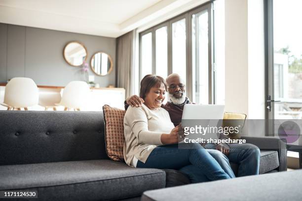 entertained in the comfort of our own home - senior couple laptop stock pictures, royalty-free photos & images