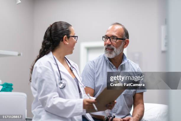 doctora femenina en consulta con el hombre adulto maduro - hombre revision fotografías e imágenes de stock