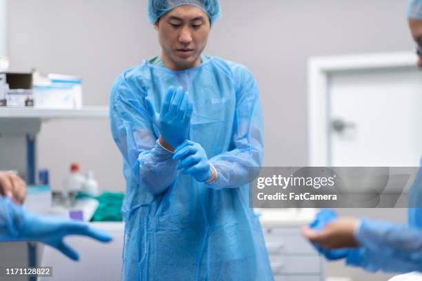 equipo quirúrgico preparándose para realizar la operación en el paciente - operating gown fotografías e imágenes de stock