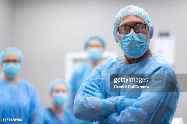 portrait of a male surgeon with medical team - doctor scrubs stock pictures, royalty-free photos & images