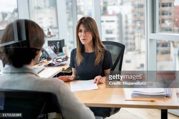 hr manager at her office talking to employee cheerfully - gerente imagens e fotografias de stock