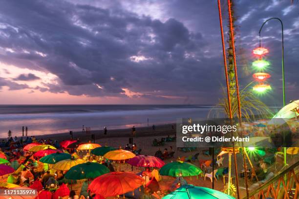 tourists and local enjoy the sunset over the famous seminyak beach in south bali near kuta in indonesia - kuta stock pictures, royalty-free photos & images