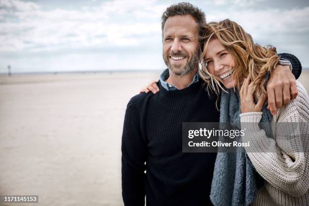happy couple hugging on the beach - zärtlich stock-fotos und bilder