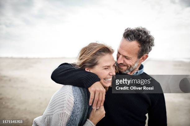 happy couple hugging on the beach - mid adult stock-fotos und bilder