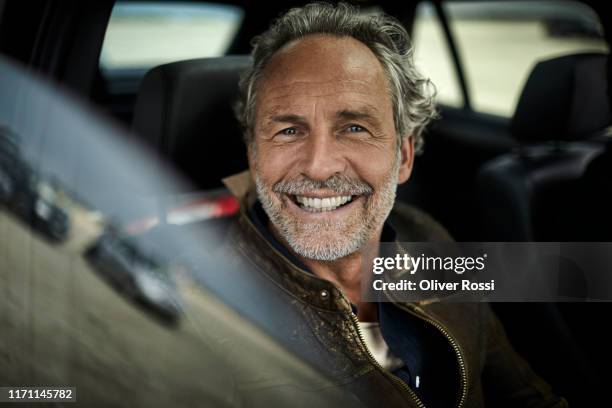 portait of happy man with grey hair in a car - homme content chez lui photos et images de collection
