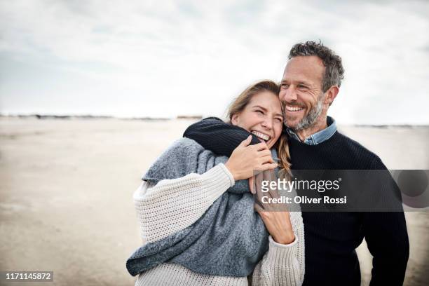 happy couple hugging on the beach - erwachsener über 30 stock-fotos und bilder