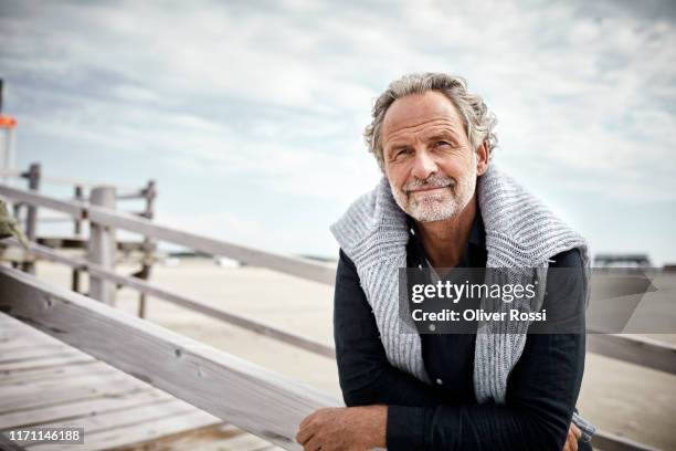 mature man standing on boardwalk on the beach - 50 fotografías e imágenes de stock