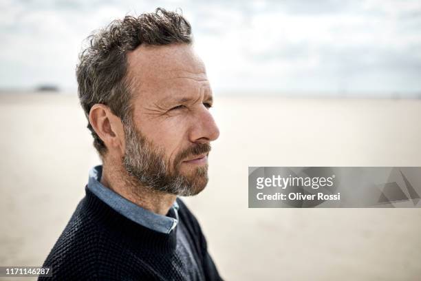 portrait of pensive bearded man on the beach - oliver fink stock pictures, royalty-free photos & images