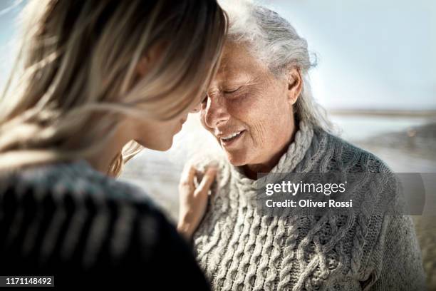 affectionate senior woman with her adult daughter on the beach - fond 個照片及圖片檔