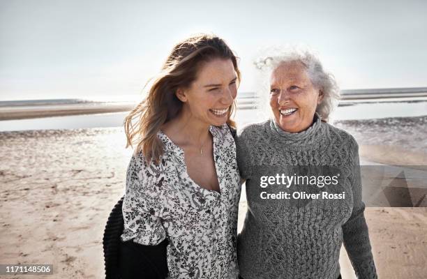 happy senior woman with her adult daughter on the beach - mother adult daughter stock pictures, royalty-free photos & images