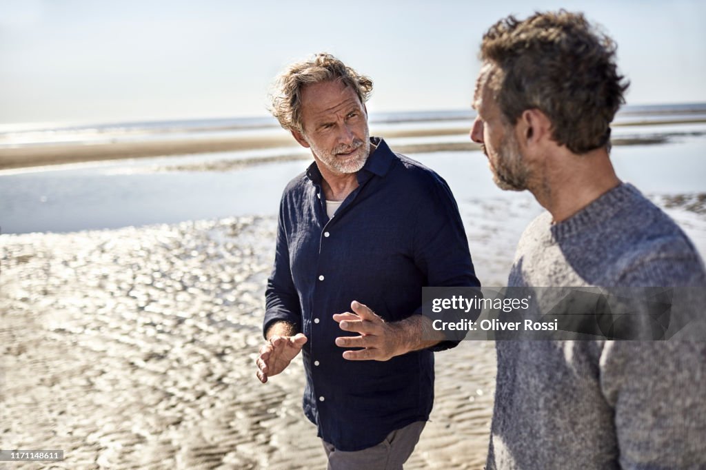 Two men walking and talking on the beach