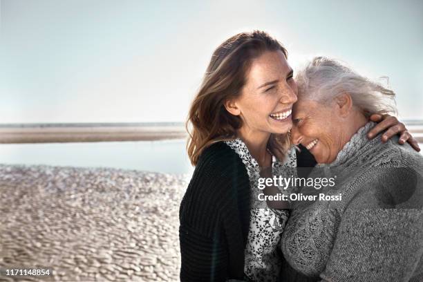 happy senior woman with her adult daughter on the beach - familie mit zwei generationen stock-fotos und bilder