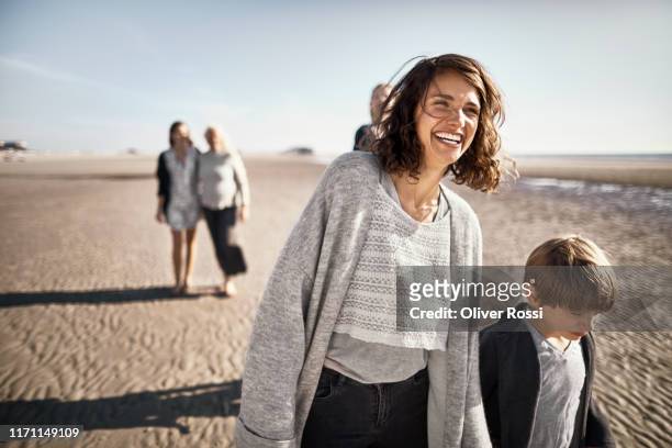happy mother and son walking on the beach - mid adult women photos et images de collection