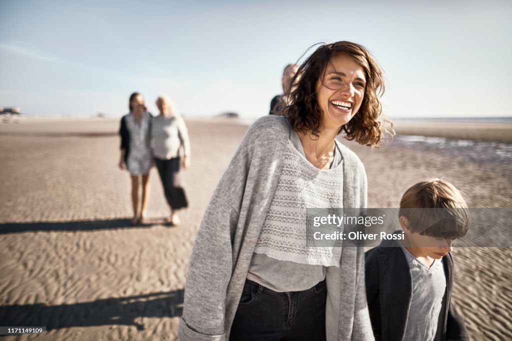 Happy mother and son walking on the beach