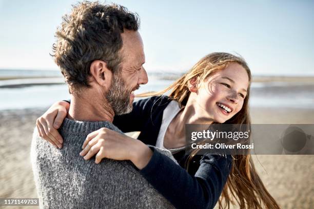 father carrying happy daughter on the beach - family holiday europe stockfoto's en -beelden