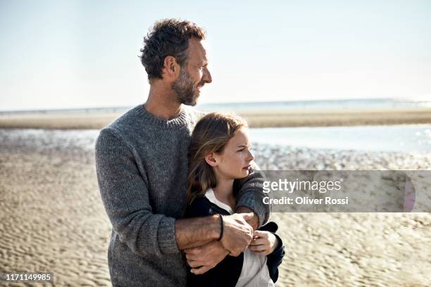 father and daughter standing on the beach - fonds marins foto e immagini stock