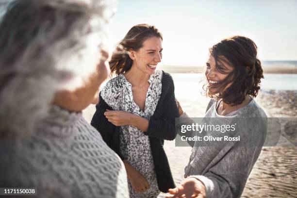 three happy women talking on the beach - familia de dos generaciones fotografías e imágenes de stock