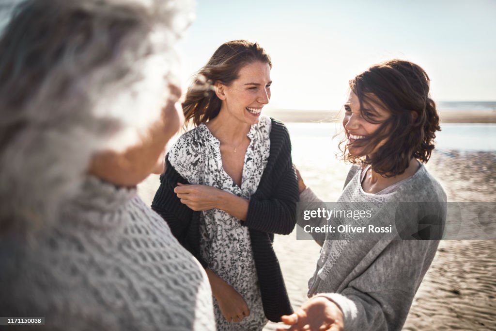 Three happy women talking on the beach