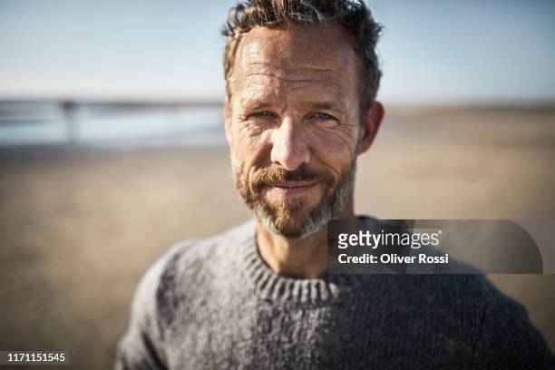 portrait of smiling mature man on the beach - uomini maturi foto e immagini stock