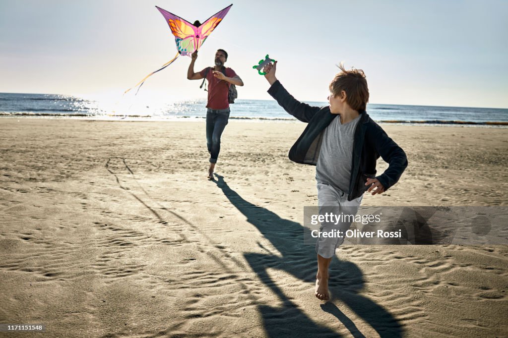 Father and son flying kite on the beach