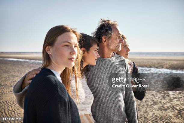 four people on the beach looking away - contemplation family stock-fotos und bilder