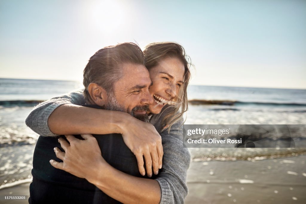 Carefree mature man and woman hugging at the sea