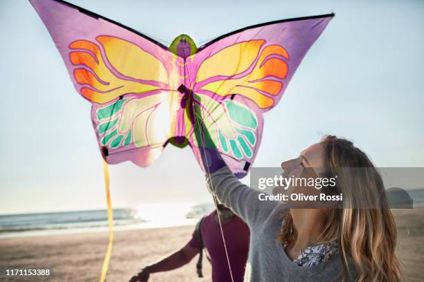 happy couple with kite on the beach - kite flying stock pictures, royalty-free photos & images