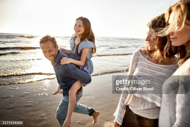 happy father carrying daughter piggyback by the sea - contemplation family stock pictures, royalty-free photos & images