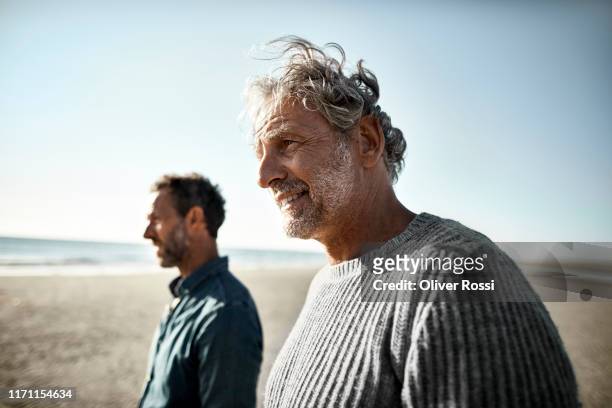 two smiling men on the beach - mature men walking stock pictures, royalty-free photos & images