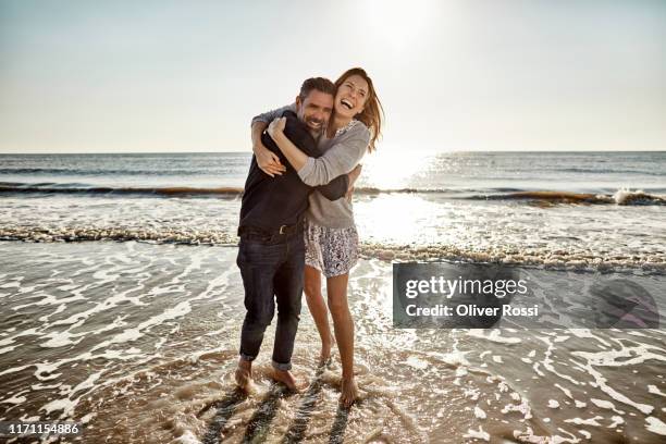 carefree mature man and woman hugging at the sea - mature woman in water stock pictures, royalty-free photos & images