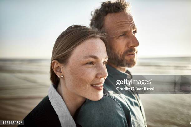 portrait of man and young woman by the sea - couple sunset beach stock pictures, royalty-free photos & images