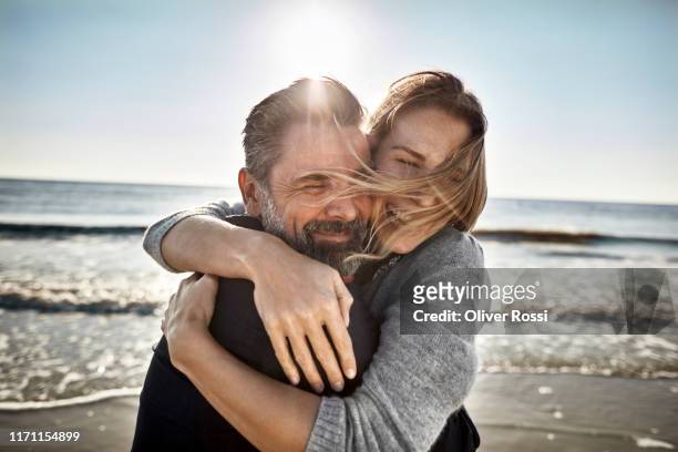 carefree mature man and woman hugging at the sea - love emotion stock pictures, royalty-free photos & images