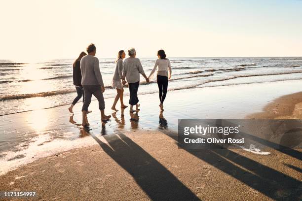 family strolling on the beach at sunset - beach walking stockfoto's en -beelden