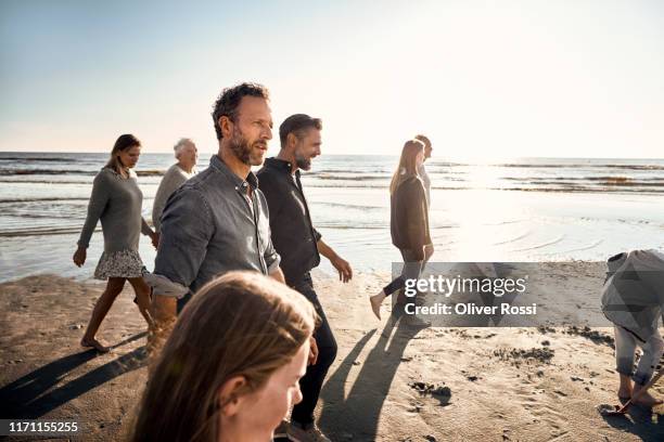 family strolling on the beach at sunset - backlit family stock pictures, royalty-free photos & images