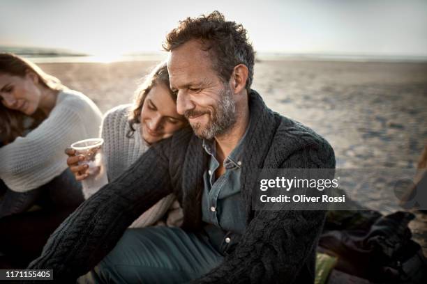 woman leaning against man's shoulder on the beach at sunset - father sun stock pictures, royalty-free photos & images