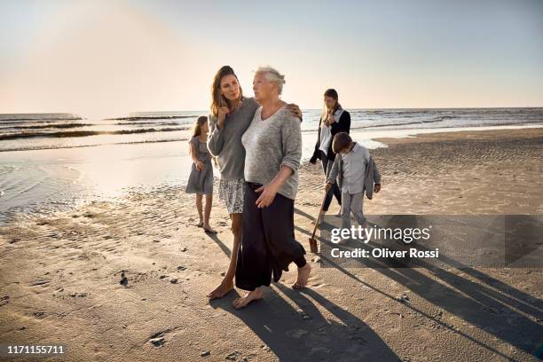 family strolling on the beach at sunset - fonds marins foto e immagini stock