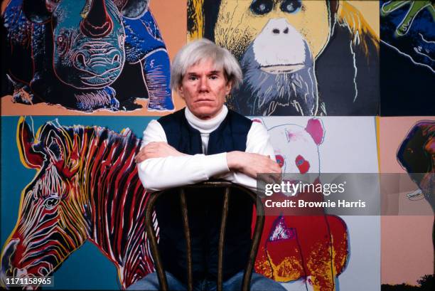 American Pop artist Andy Warhol sits in front of several paintings in his 'Endangered Species' at his studio, the Factory, in Union Square, New York,...