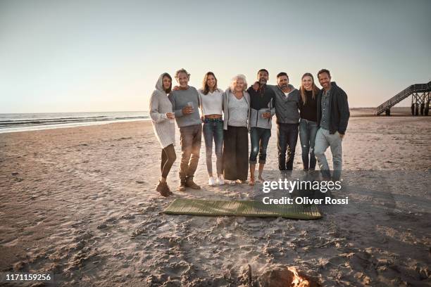 portrait of family and friends on the beach at sunset - group photo stock-fotos und bilder
