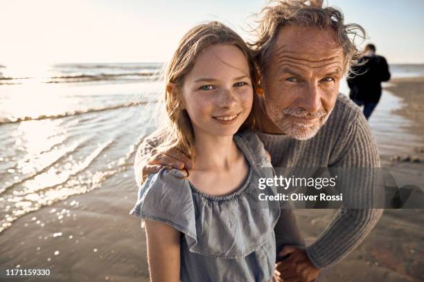 portrait of granddaughter with grandfather on the beach - three generation family stock pictures, royalty-free photos & images