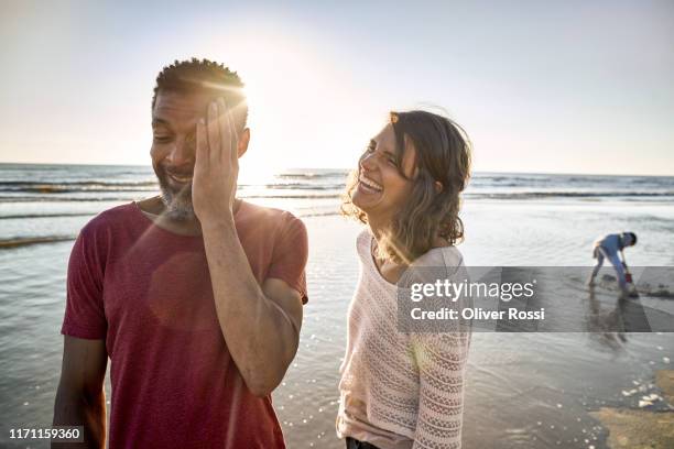 laughing young woman and mature man on the beach - backlit family stock pictures, royalty-free photos & images