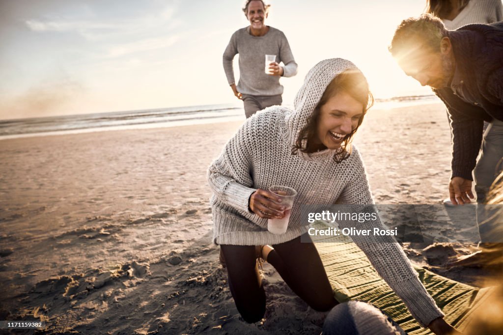 Happy woman with friends and family on the beach at sunset