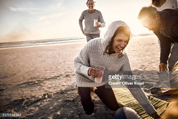 happy woman with friends and family on the beach at sunset - holiday drinks stock-fotos und bilder