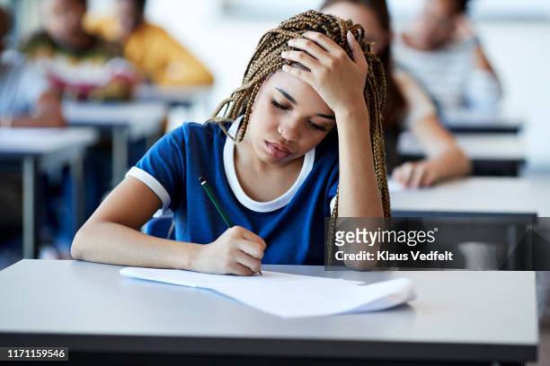 young braided hair woman writing exam at desk - stressed student stock pictures, royalty-free photos & images