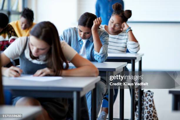 young multi-ethnic female students writing exams - school system stock pictures, royalty-free photos & images