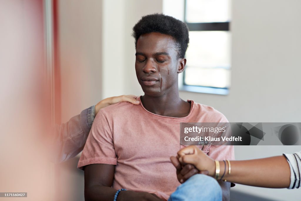 Young female friends consoling sad crying man