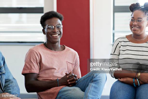 smiling man sitting amidst friends during therapy - team t shirt imagens e fotografias de stock