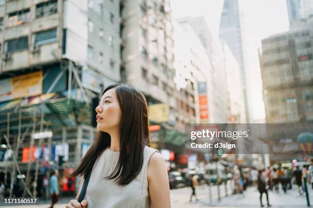 young woman looking far away in city with local street scene in hong kong - fashion hong kong stock-fotos und bilder