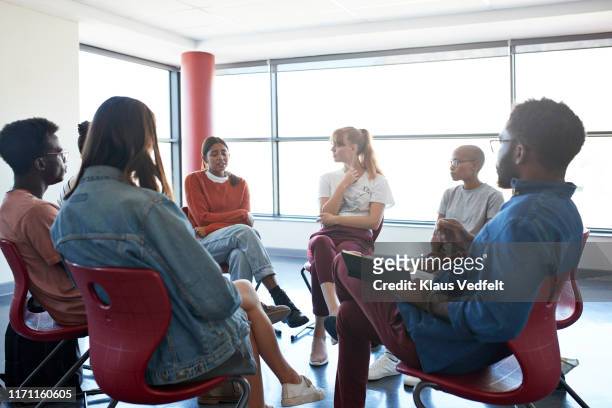 sad woman sharing with friends and instructor - group counselling stock-fotos und bilder