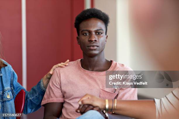 sad man being consoled by friends in group therapy - african man imagens e fotografias de stock